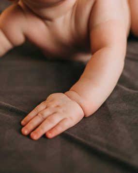 Bébé en couche qui pousse sur ses bras, début de la motricité et de l’exploration.